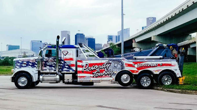 Priority Towing heavy wrecker hauling a tractor — trucking and logistics